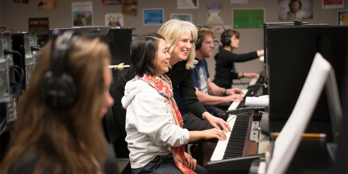 AACC students learn to play piano with the help of instructor.